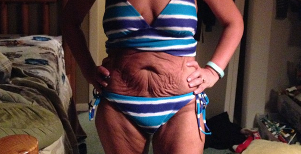 Kvinna i blårandig bikini poserar i ett rum En randig bikini klär en härlig mage